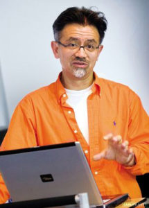 996-gen Porsche 911 Buyer Guide: Depicted here is a portrait of Pinky Lai wearing an orange Polo shirt at a podium with a laptop computer. Credit: carlife.net