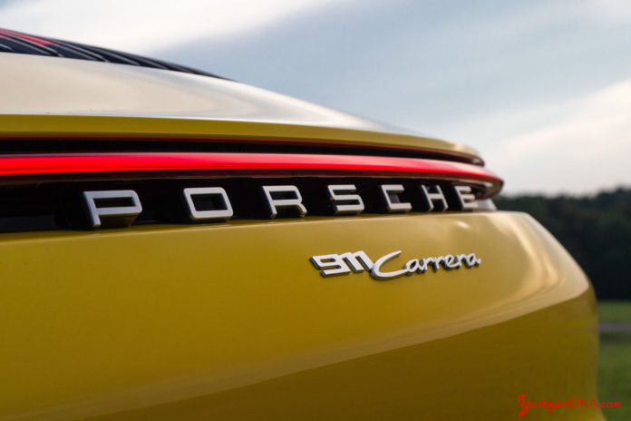 October 2019 USA Sales: This photo is a tight shot of the rear “Porsche 911 Carrera” badging and illuminated continuous red taillight strip on a Racing Yellow 911. Credit: Porsche AG