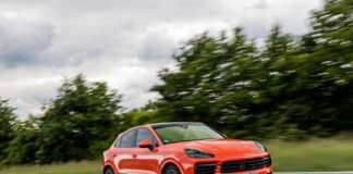 November 2019 Porsche USA sales November 2019 Porsche USA sales: This is a photograph of a lava-orange Cayenne coupe, right-front, at speed on a deserted road, with tall green bushes and a cloud-filled sky in b.g. Credit: Porsche AG