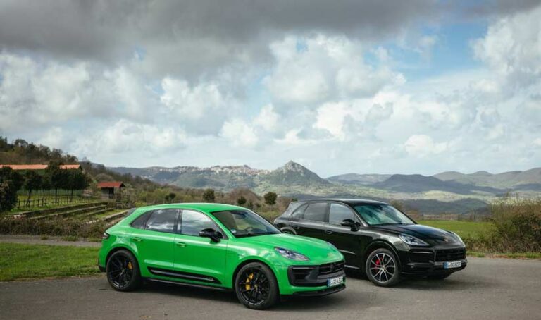 Depicted in the image are two green and black Cayennes against the backdrop of countryside and several mountain peaks in deep b.g. Credit: Porsche AG