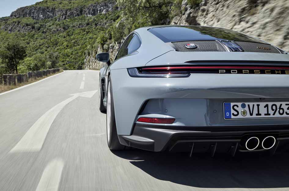 911 S/T - Depicted here is a 911 S/T, seen low from its left-rear, sweeping fast along a mountain road. Credit: Porsche AG