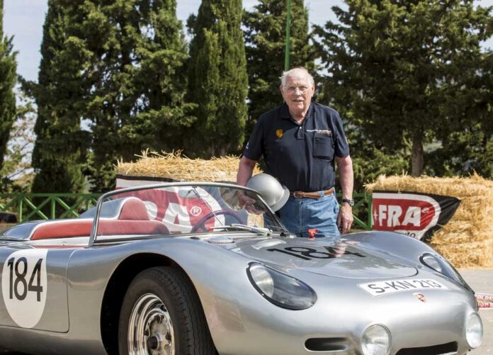 Herbert Linge is seen here posing with a Porsche 718, a racecar he is very familiar with driving and repairing.