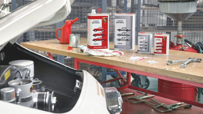Pictured her is a display of Porsche Classic Motoroil in the background of a 356 in garage. Credit: Porsche AG