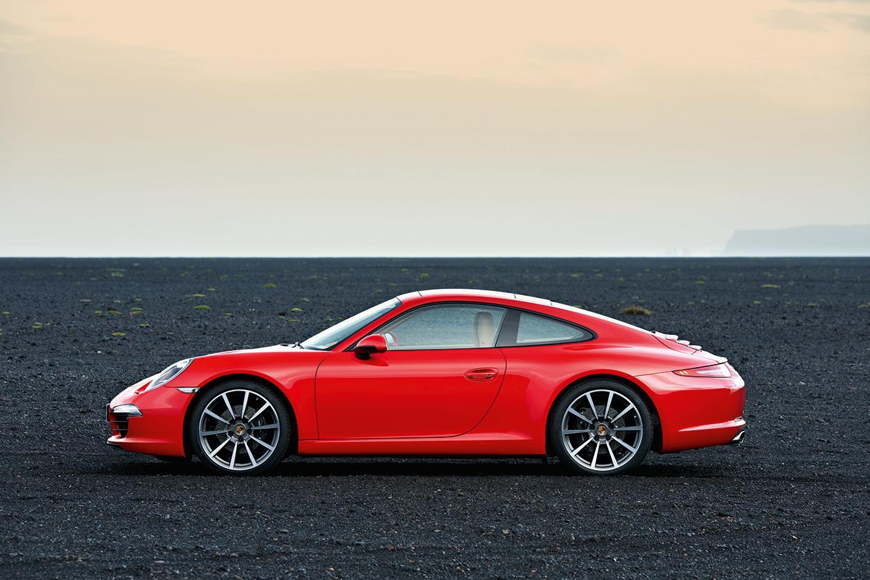 991.1-Gen Porsche 911 Buyer Guide: Pictured here is an Orange 991.1 Coupe - left side on black rock. Credit: Porsche AG